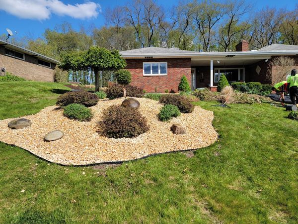 Professional landscaping with decorative stone bed and trimmed shrubs