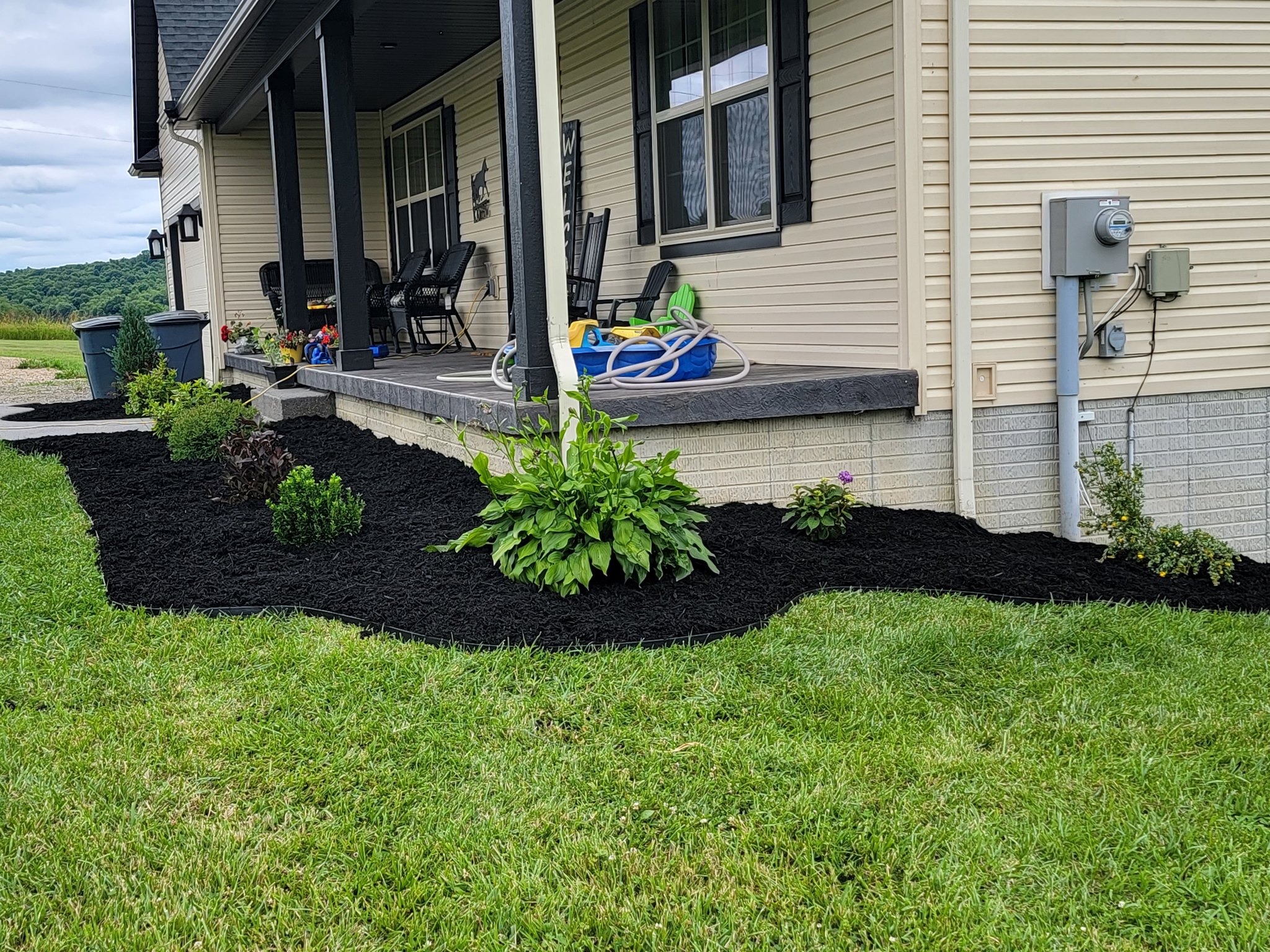 Fresh black mulch front bed with plantings along porch